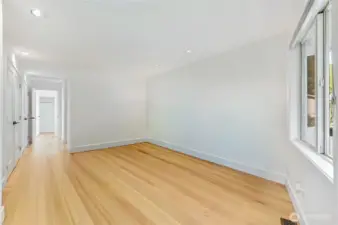 Same view as the last photo of the main level primary bedroom space un-staged. There's a door to the right that leads to the covered patio, and on the left is a row of closets with new doors.