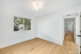 The main level guest bedroom has a quarter bath just outside the door.  The view in the background looks into the primary bedroom.  Sellers use this room as their den.