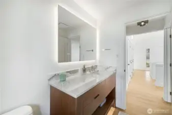 Completely updated, the powder room has modern finishes, a back-lit, adjustable electric mirror and is conveniently located by the main level guest room. The French door in the background is the front entry.