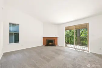 Living room with wood burning fireplace, vaulted ceilings, and door to balcony and storage