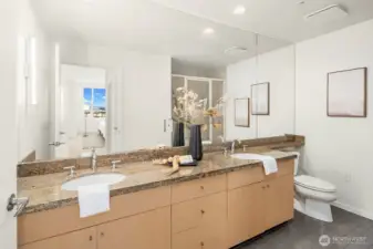 En-suite primary bath with dual vanity topped by slab granite.