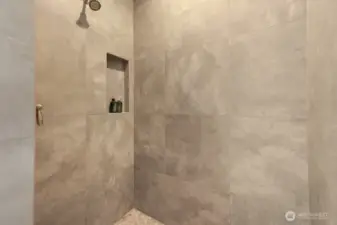 Hallway bathroom on the main floor features a custom, handmade vanity, walk in shower, and large format tiles on floor and shower.