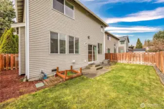 A quaint and cute backyard with garden area and sprinkler system.