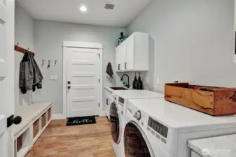A well-appointed mudroom designed for effortless organization. Imagine kicking off your shoes and hanging up coats before entering the main house. This practical space features a conveniently located washer and dryer and sink making laundry a breeze.