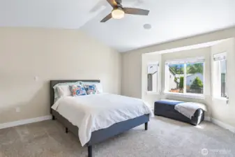 Primary bedroom with vaulted ceilings and bay window that overlooks the backyard.