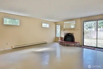 Spacious living room with sliding glass doors to the backyard. Wood stove! Subfloor is painted. Your back is to the hallway and the dining area is beyond the left edge of this photo.