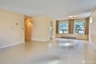 With your back to the wood stove, you are looking back at the dining area with the entrance to the kitchen and the entrance of the hallway that leads to the front entrance and the bedrooms and bathrooms.
