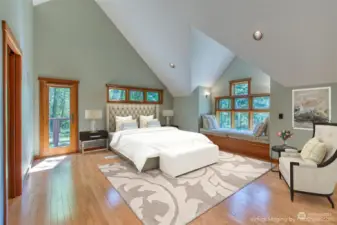 The primary bedroom is flanked by a large bay window seat, a balcony deck, and a large walk-in closet.