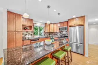 Large, fully updated kitchen with granite counters, abundant cabinetry, newer stainless steel appliances including gas range, and large breakfast bar center island.