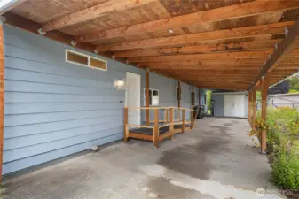 View from large carport towards door to laundry room - note the additional storage shed/shop space with electrical straight ahead.