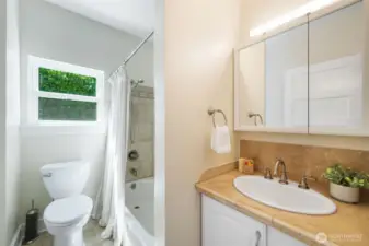 Full bath with ceramic tile surround and vanity with ample storage.