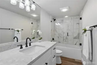 Remodeled hall bath with glass enclosed tub/shower.