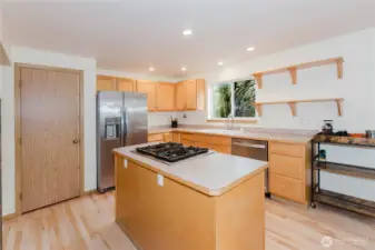 This kitchen features a center island with cooktop, a pantry for added storage, and stainless appliances.
