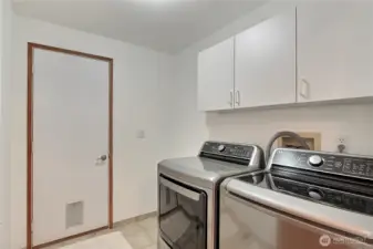 View of your utility room leading to your garage, newer included washer & dryer and love all the storage cabinets.