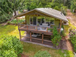 Expansive covered deck and charming daylight basement offer flexible indoor-outdoor living with views of lush greenery and surrounding nature. The perfect perch for your morning coffee or a quiet evening unwind, just minutes from the Fox Island Bridge.