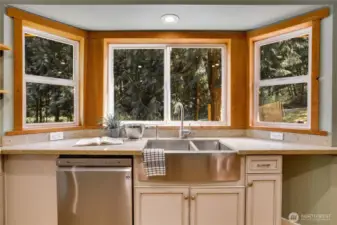 Enjoy ample counter space, stainless appliances, and a farmhouse sink overlooking lush greenery.
