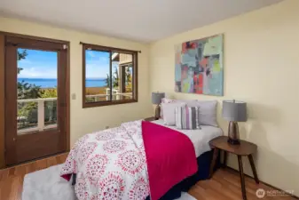 The main level includes a bedroom wing with three bedrooms and a full bath. This first bedroom features laminate flooring, beautiful views, and access to a private deck shared with the adjacent room.