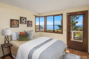 The second main-level bedroom also features laminate flooring, views, and access to the shared private deck.
