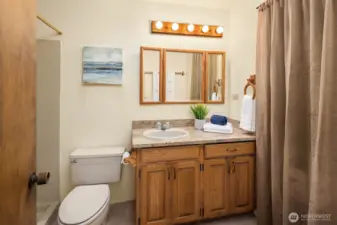 The lower-level three-quarter bath features slab granite counters. Behind the curtain is a space originally planned for a sauna, now used for storage.