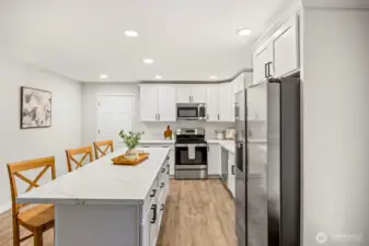 Kitchen with quartz counters, white cabinets, stainless steal appliances  & large island with seating