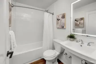 Main floor full bath with lovely new designer tile surround, new bathtub and dimmable LED vanity mirror.