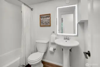 Full bathroom with fresh designer tile surround, new LVT flooring and dimmable LED mirrored vanity.