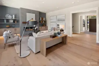 The Great Room on the main level (to the right you can see the front door Entrance).This space is designed for both style and functionality, featuring custom-built cabinets, sleek open shelving, and a striking 60-inch electric fireplace with a beautiful wood mantel. TV Included, ceiling-mounted surround sound speakers, this room is primed for the ultimate entertainment experience.