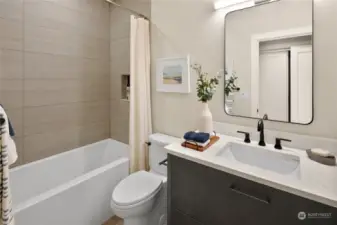 The Guest/ADU bathroom is beautifully designed with a shower/tub combination, sleek toilet, and a stylish sink. Finished with Belmont cabinets and a polished quartz countertop, this space exudes both elegance and functionality.