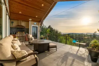 The covered deck offers a built-in grill, cozy seating, and sweeping sunset views over the islands and treetops.