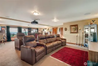 The lower-level theater room is perfect for movie nights or game days, featuring tiered seating, a projector, and scenic views.