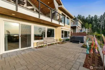 The lower patio offers easy access to a private hot tub, landscaped garden beds, and sweeping views of the islands and water.