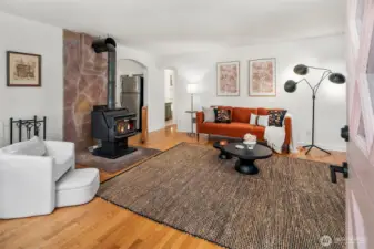 Warm and welcoming living room has a cozy wood stove and hardwood floors.