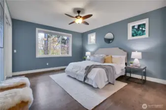 Serene primary suite with remote Hunter Douglas window coverings.  Engineered hardwood floors. Sliding door to porch on your left.  Bath to right.  Note clerestory windows above bed.