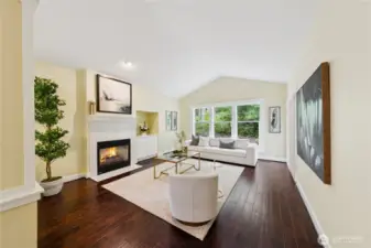 Spacious living room featuring a natural gas fireplace and views of the backyard and patio, creating a cozy and connected indoor-outdoor feel.
