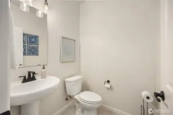 Lower level half bath features ceramic tile and black fixtures.
