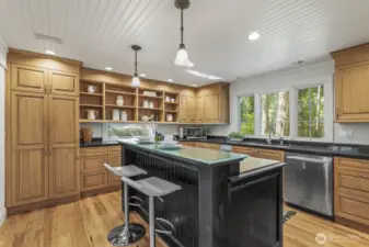 The kitchen boasts custom cabinetry, butcher block island with a Wolf gas and electric range, breakfast bar seating, stainless steel appliances including Wolf double ovens.