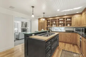 The kitchen boasts custom cabinetry, butcher block island with a Wolf gas and electric range, breakfast bar seating, stainless steel appliances including Wolf double ovens.