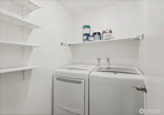 In-unit laundry room with storage shelves.