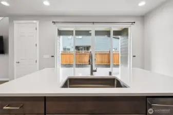 Kitchen island with eat at bar, stainless steel undermount sink, quartz countertops & large slider out to your covered patio area.