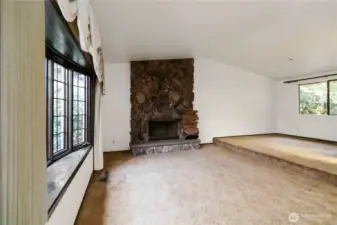 Spacious living room featuring a dramatic floor-to-ceiling stone fireplace and abundant natural light