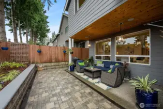 The backyard space is a tranquil oasis with a covered area, custom patio/rock wall and privacy fence.