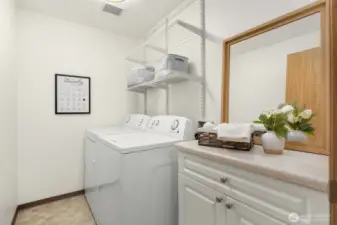 Dedicated laundry room with shelving and countertop for folding.