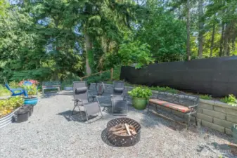 Expansive fenced in backyard with fire pit.