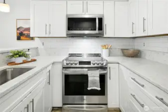 Updated kitchen boasts stainless steel appliances, white wood cabinetry, quartz countertops and a subway tiled backsplash.