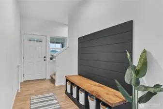 As you enter, you will find gorgeous flooring throughout, stairs up to your left, and this beautiful, included custom bench in the hallway with storage!