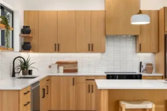 The view looking from the dining area; additional details include lighting under cabinetry and open shelving.