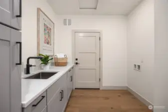 Laundry room with quartz counters and storage doubles as a mudroom. The door leads to the two car garage. Note: ceiling access to 190 sq ft of storage.