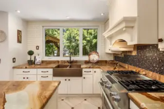 Rustic charm meets elegance in this open-concept kitchen with stone countertops, copper sink, and tree-lined views.