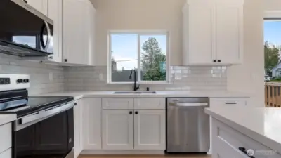 Kitchen has quartz counters and tile backsplash.