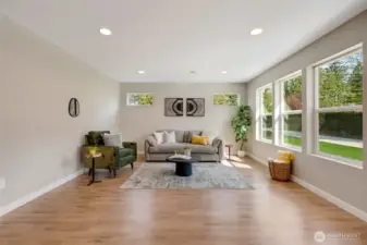 The living room features plenty of windows, creating a warm and inviting space with morning sunlight.